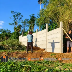 Pekerja Memasang Pagar Beton di Lahan Hijau
