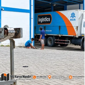 Pekerja Memperbaiki Paving di Gudang Logistik