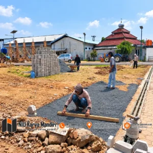 Pemasangan paving block segi enam Pekerja Meratakan Dasar Paving di Lokasi Konstruksi